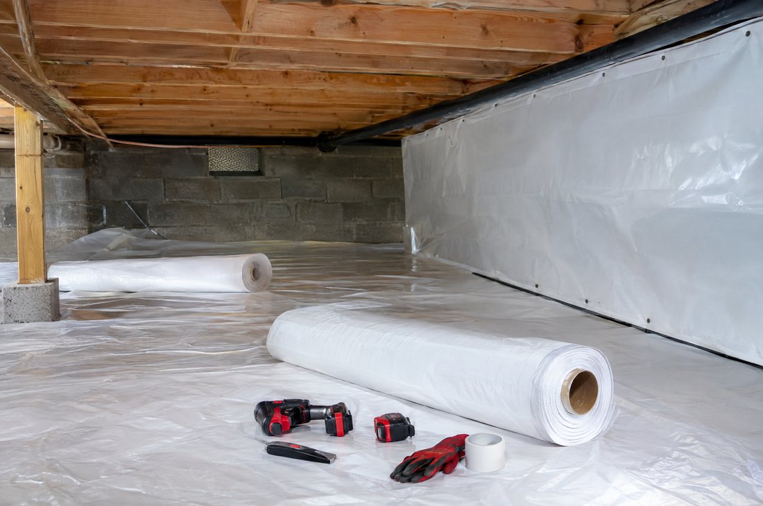 Crawl space technician installing a vapor barrier in Asheville, NC